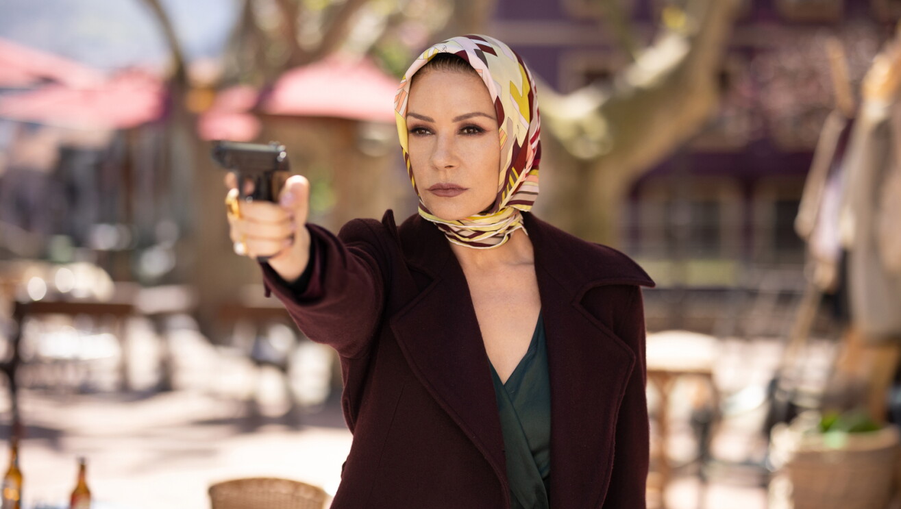 Catherine Zeta-Jones as Jackie Price points stares down the sights of a pistol.