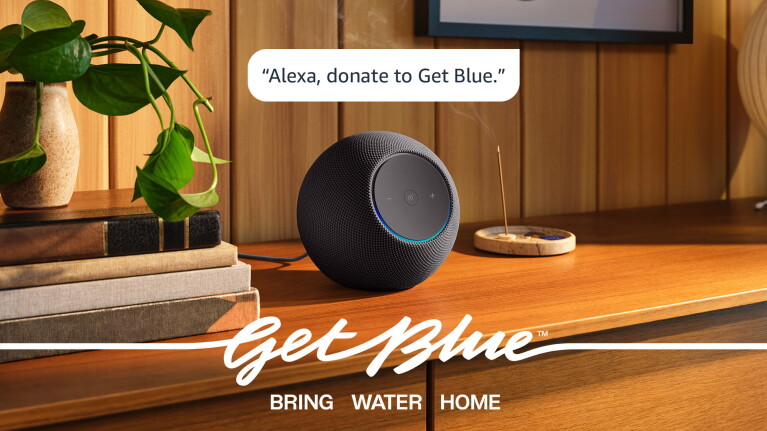 Alexa smart speaker on wooden table with Get Blue branding and tagline 'Bring Water Home'