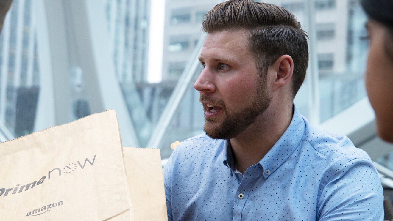 A man holds a Prime Now package.