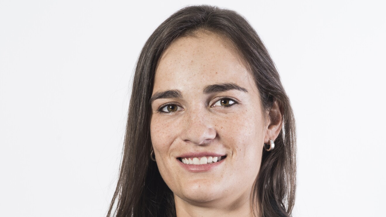 Eugenia. Pelo largo castaño liso, pendientes, sonriendo a la cámara y con los ojos también castaños.
