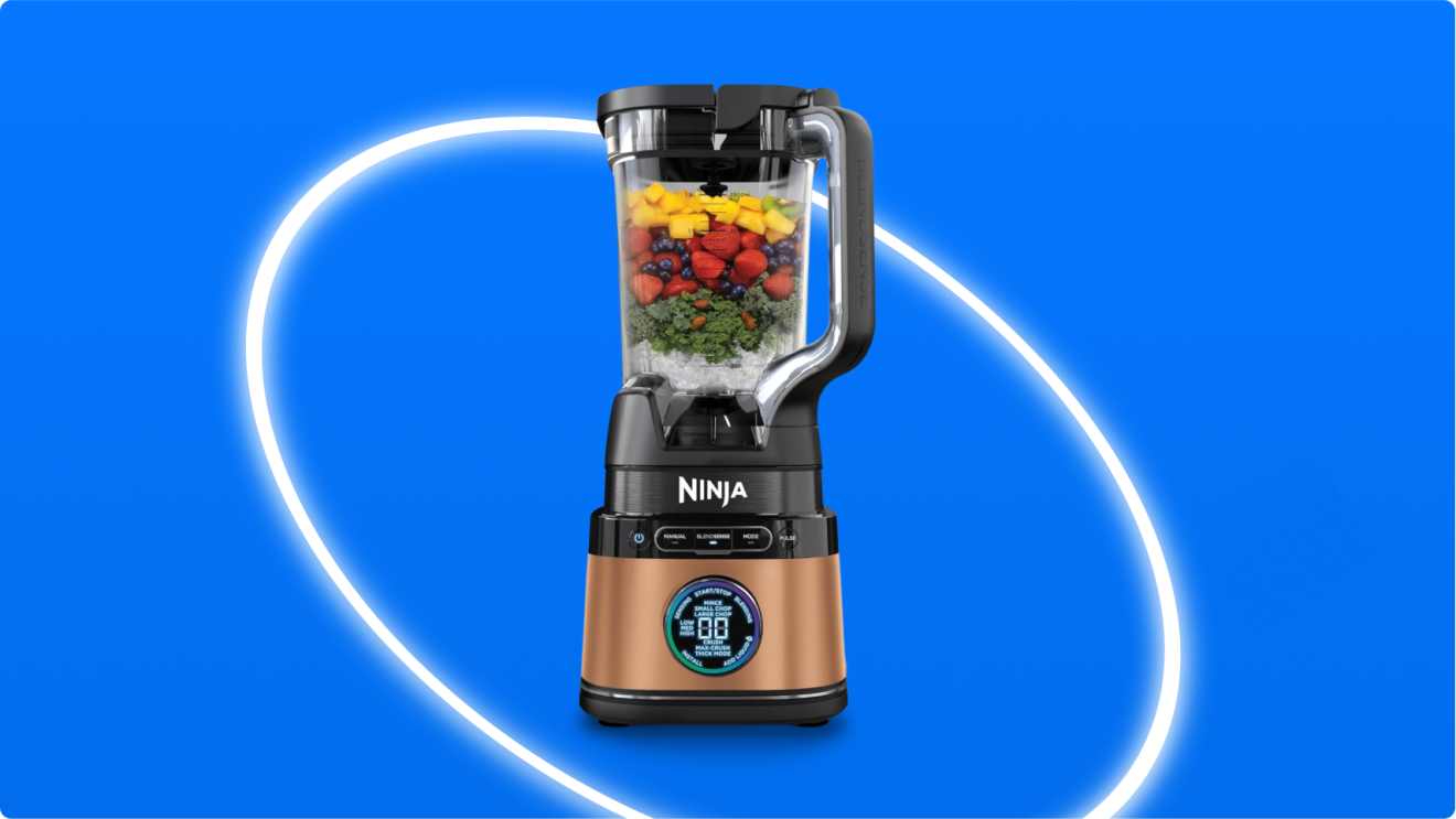 Ninja blender filled with colorful fruits and vegetables on blue background