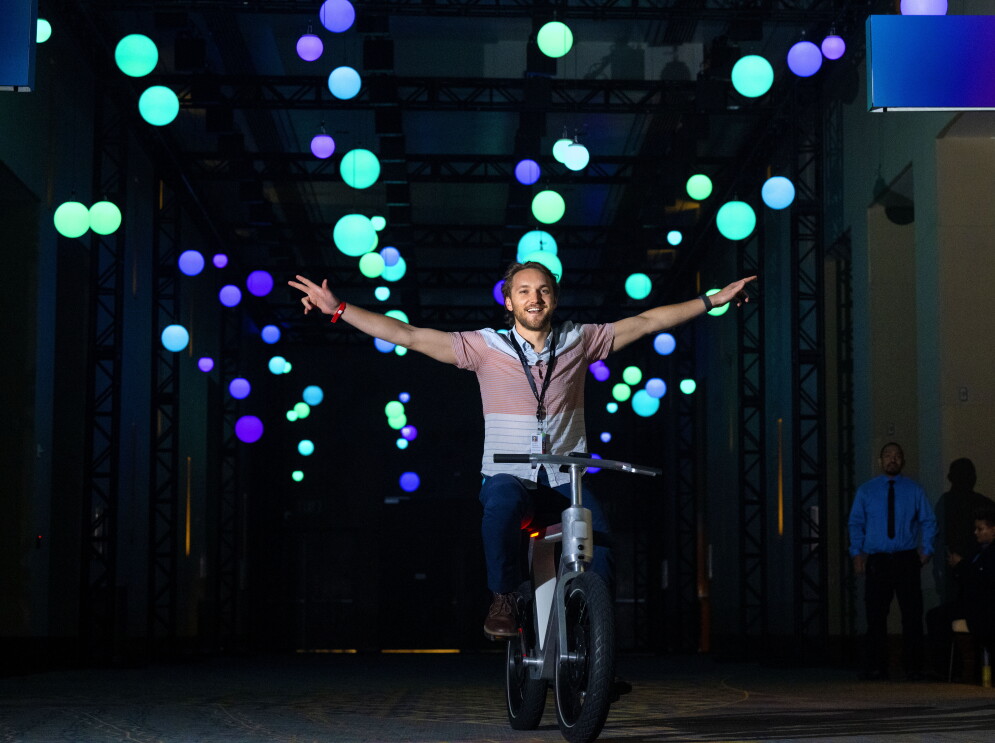 An image of a man on a Weel bike. He has his hands up and is riding with no hands. 
