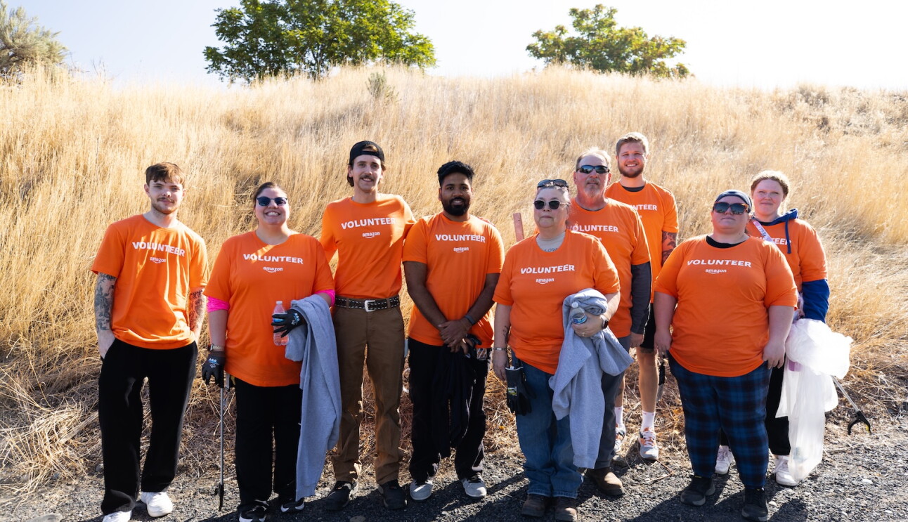Amazon data center employees in volunteer shirts smile together along Old River Road in Umatilla, Oregon after a community cleanup event.