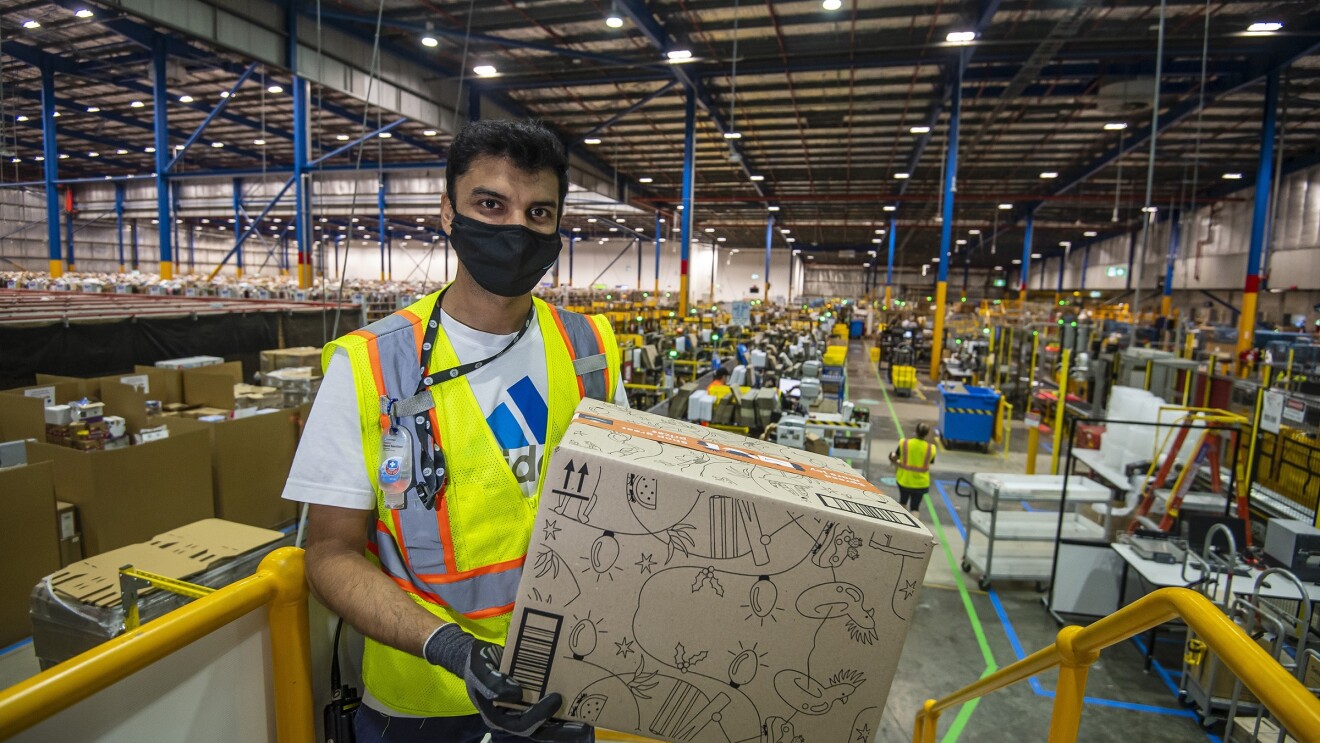 Siraj, an Amazon Warehouse Associate holding a box