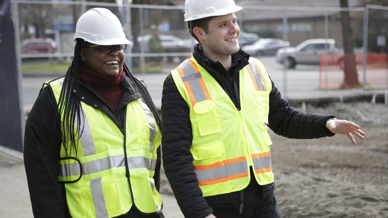 Two professionals in hard hats and hi-vis vests on job site