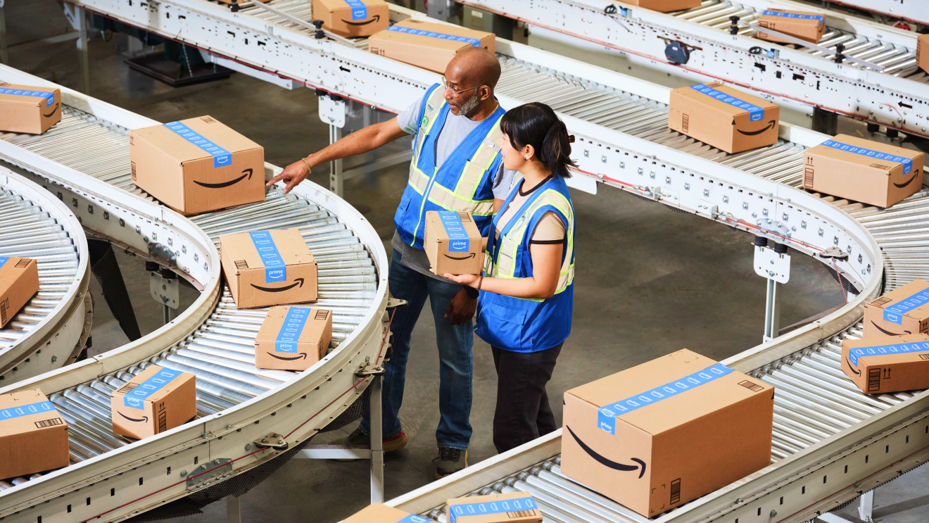 Fulfillment associates surrounded by conveyor belts moving with Amazon boxes.