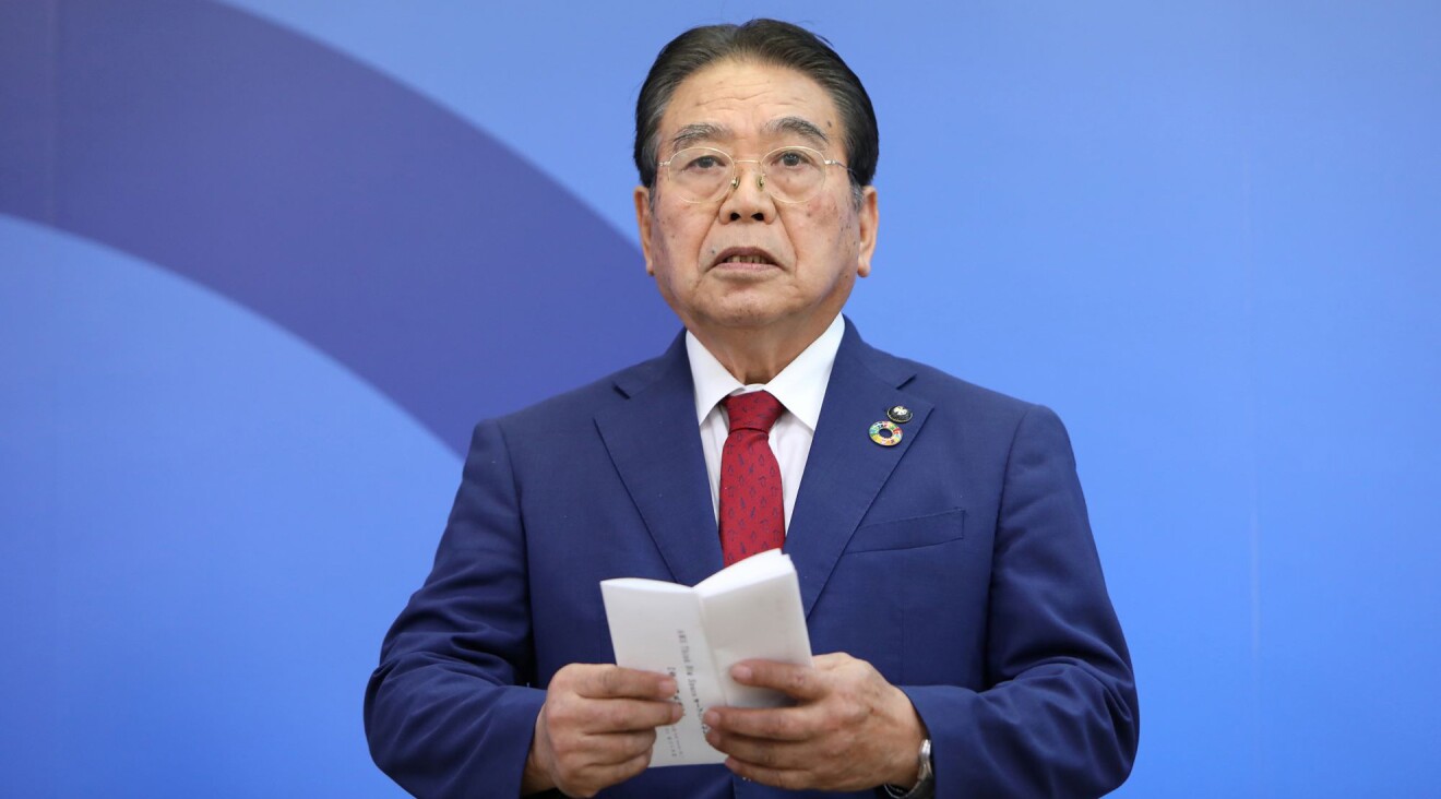 紺色のスーツを着た男性が祝辞が書かれた紙を手にしている