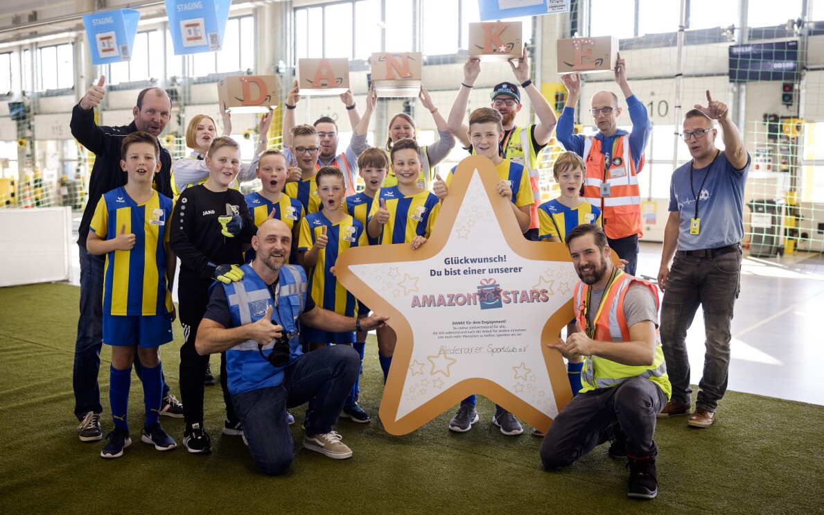 Amazon Star Enrico mit den Fußballkids, die er trainiert, im Sortierzentrum.
