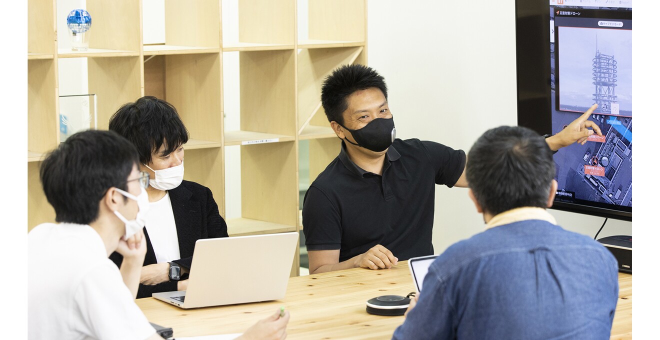 モニターに映されたシステムを見ながら社内ミーティングをしている写真