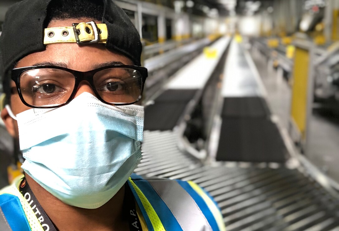 Close-up of a man wearing a protective mask in a large workspace.