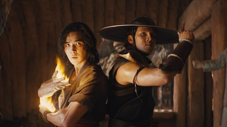 Two men standing back-to-back. Man on the left has long dark hair and a glowing fire effect on his hand, the man on the right wears a wide-brimmed hat