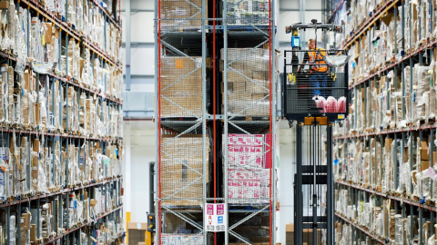 Massive shelves in Amazon fulfilment centre with man on lift retrieving items