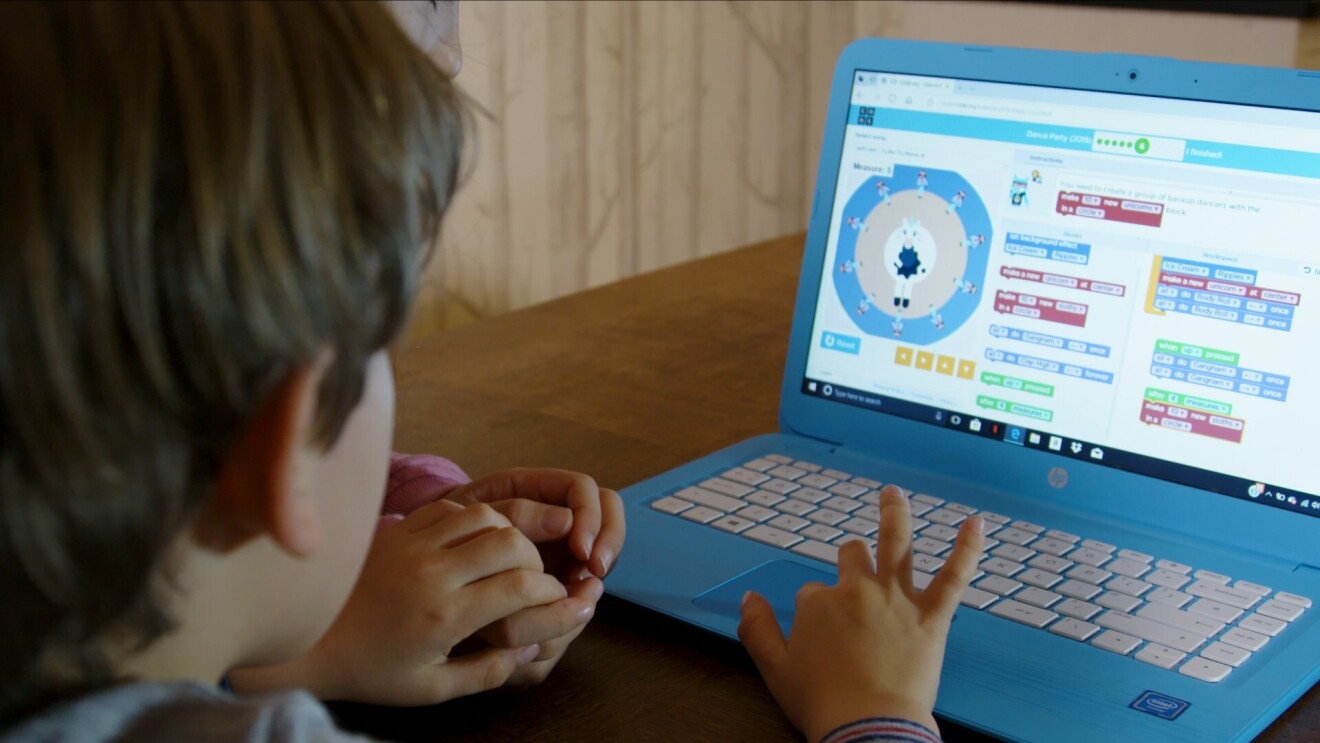 Child using Hour of Code software on a blue laptop