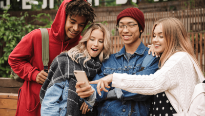 四个少年们围坐,兴奋地看着少年的一个电话。