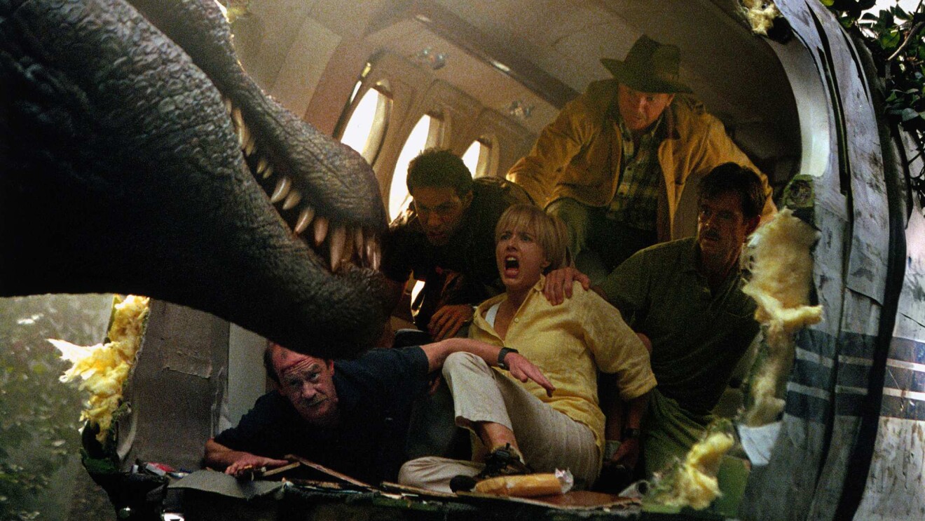 Dinosaur attacks terrified group inside damaged airplane.