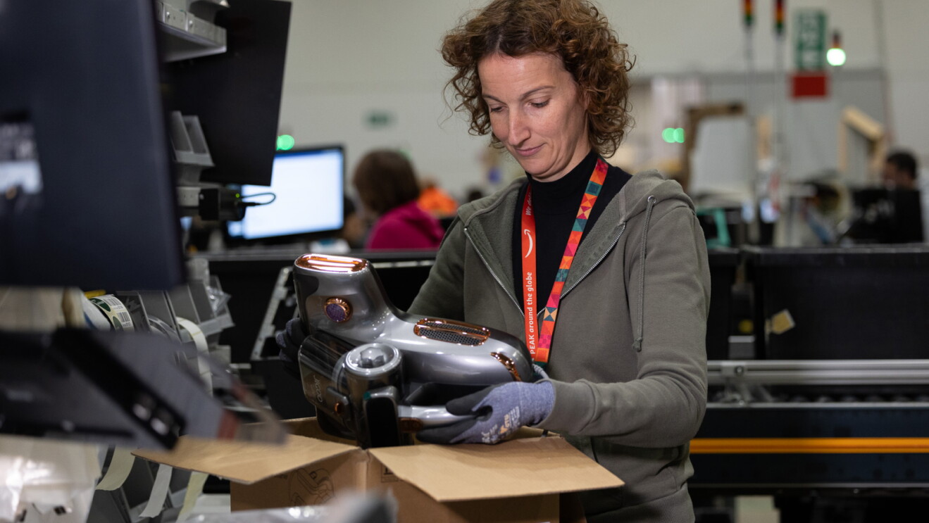 An Amazon fulfillment center worker inspecting a returned appliance