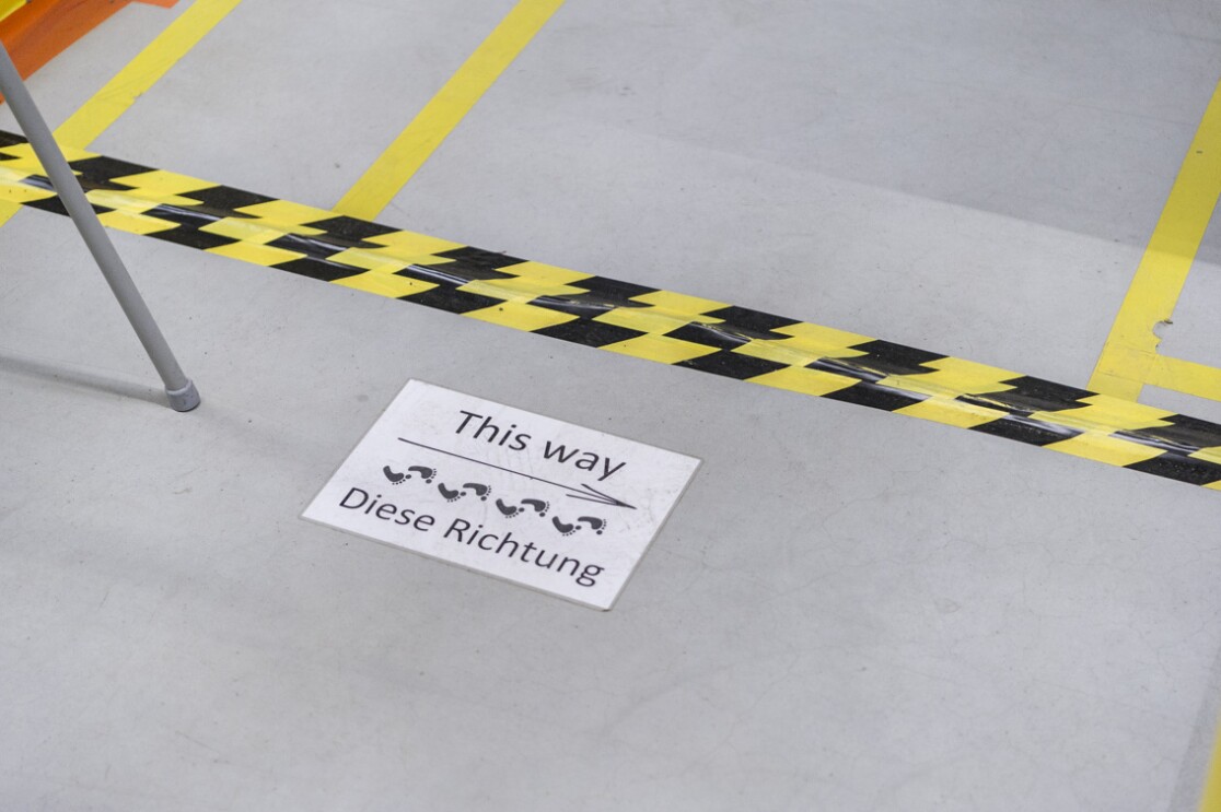 Auf dem Boden einer Lagerhalle wurde ein Schild mit der Aufschrift "This way - diese Richtung" angebracht.