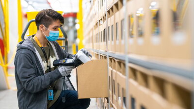 An Amazon employee wearing a face mask scans an item in a fulfilment centre.