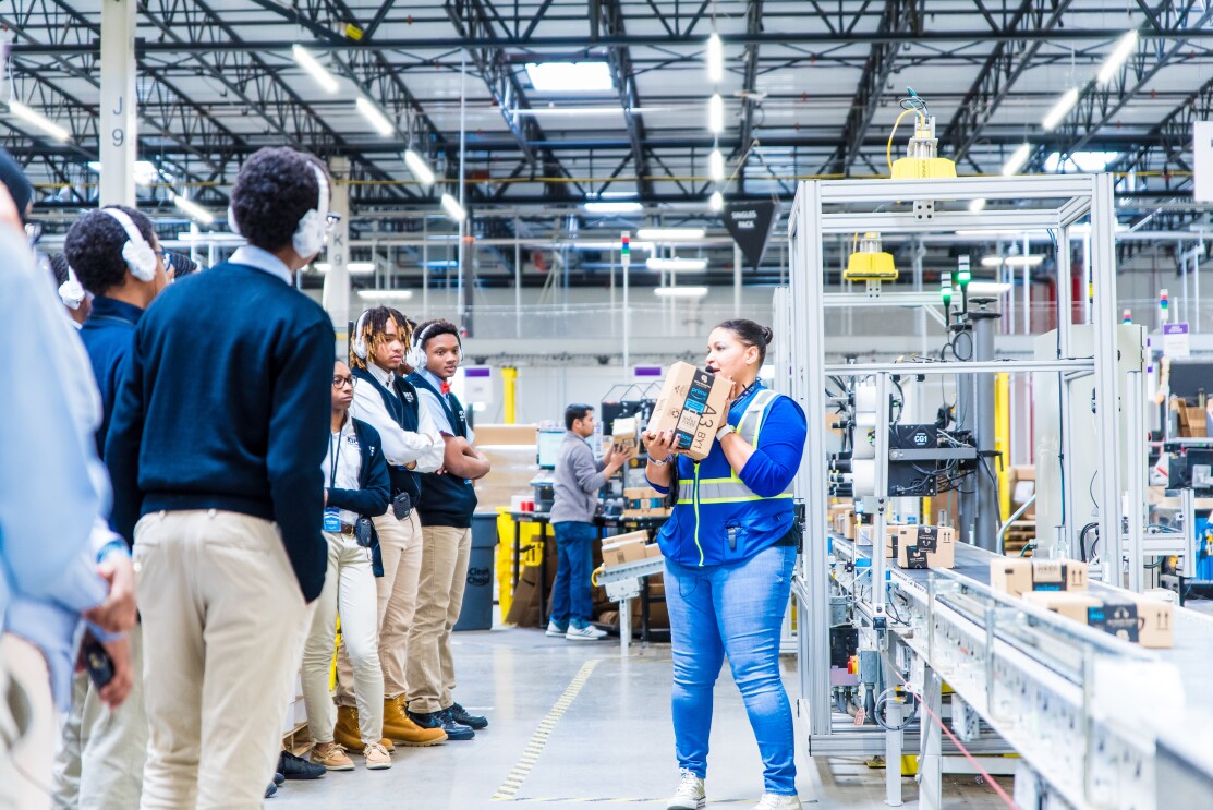Students attend a tour of an Amazon robotics fulfillment center