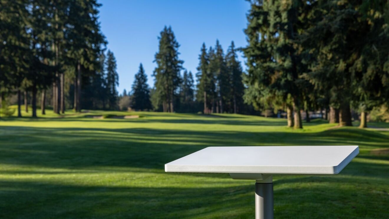 White rectangular panel on a post overlooking a tree-lined golf course fairway