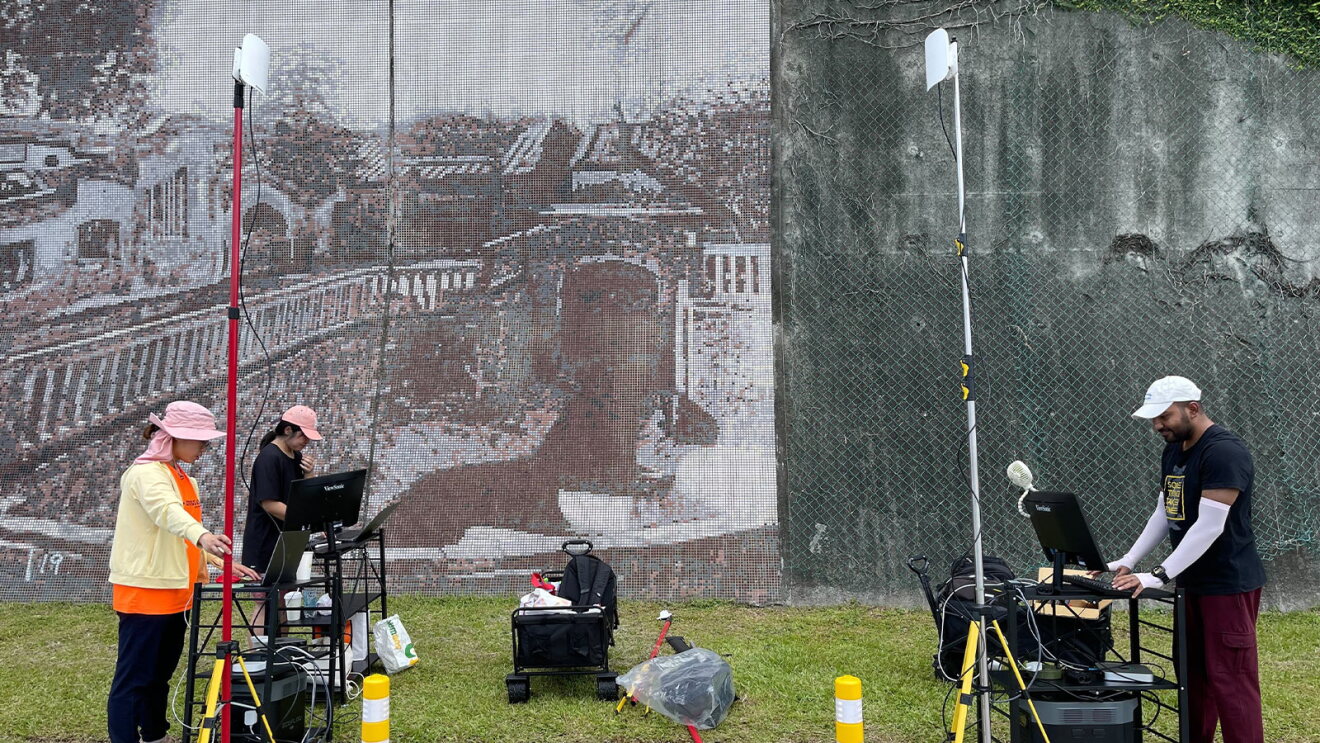 Field technicians operating gear near wall with city scene