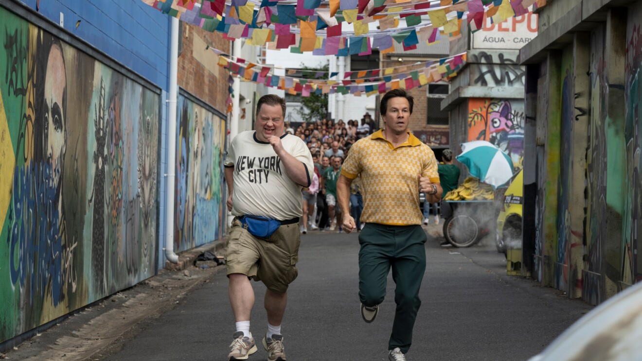 Two men running through colorful alley with festive flags overhead
