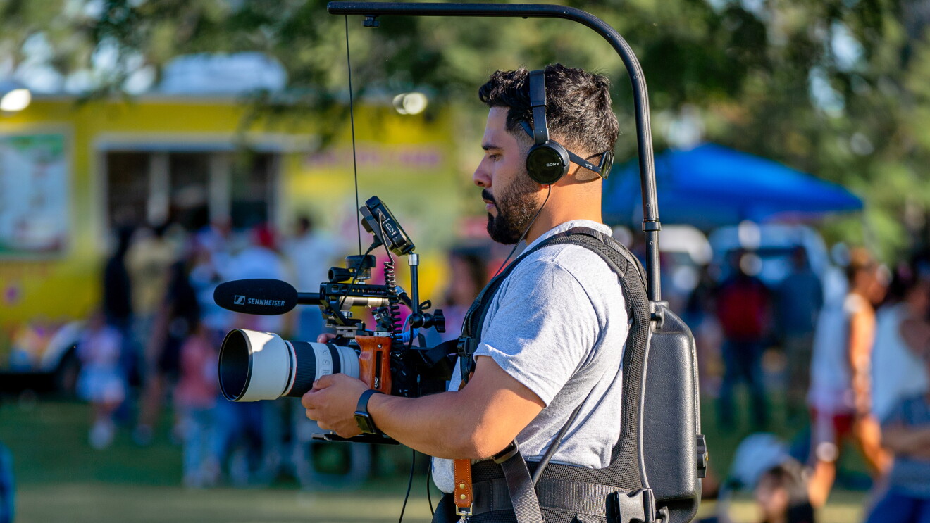 Mario Sepulveda involvement with AWS: Cameraman with professional gear filming outdoor event