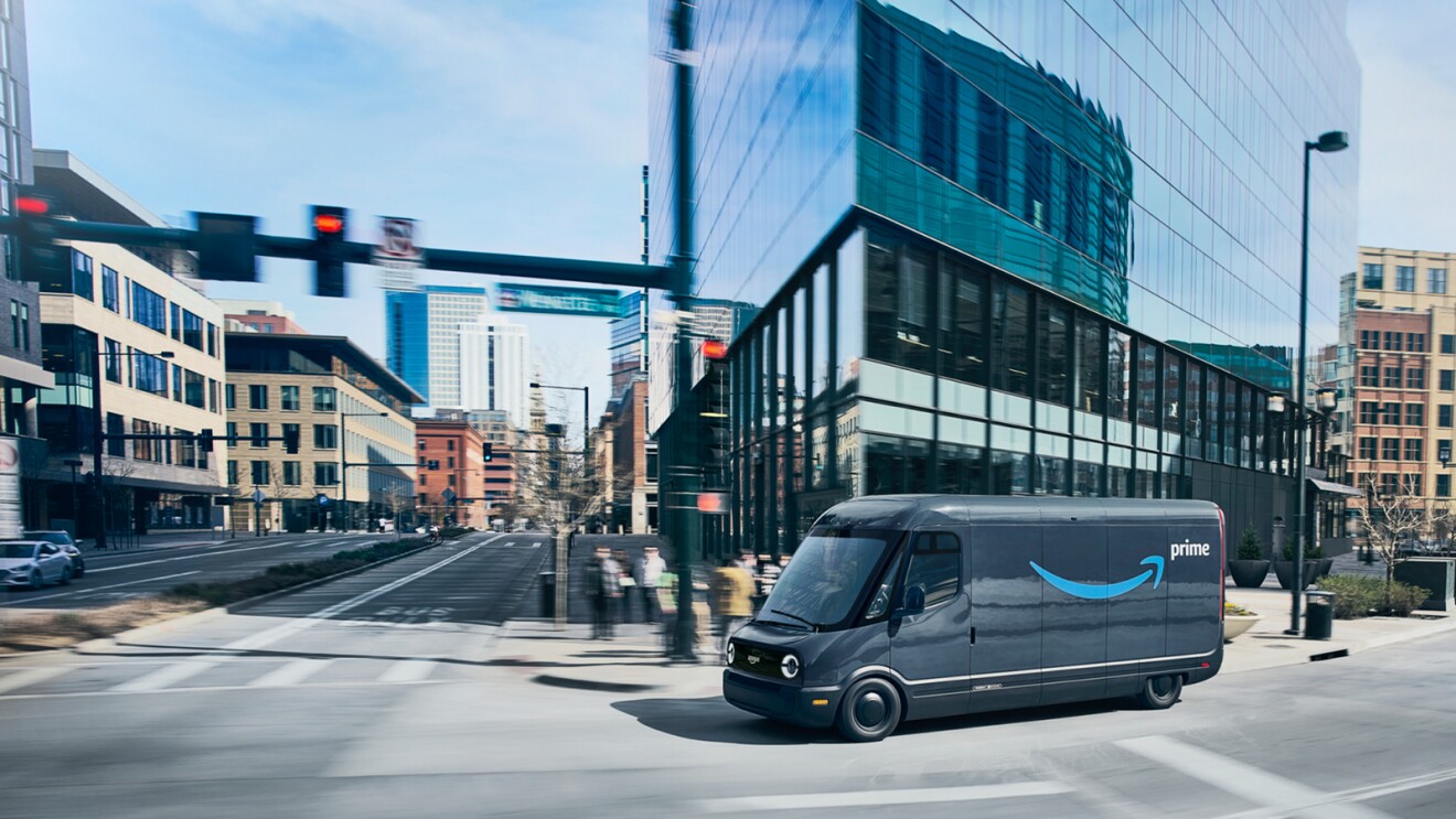 Furgoneta eléctrica de Amazon con el logo de Amazon Prime circulando por una gran ciudad.