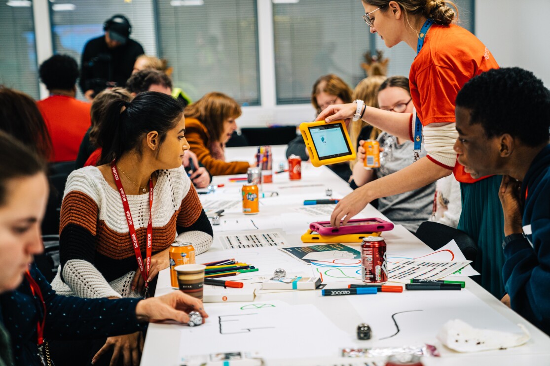 Row of children from Barnardo's doing arts and crafts at robotics workshop. They are also being handed tablet computers.