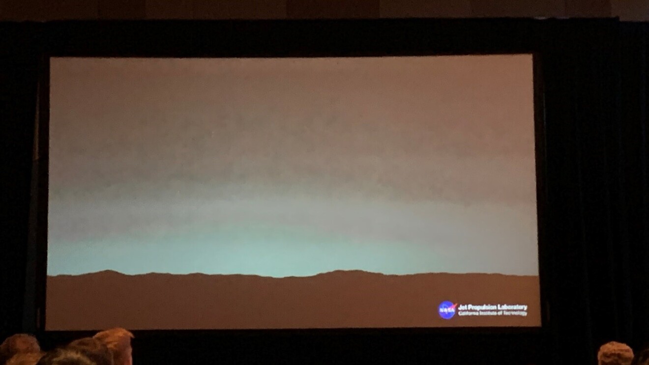 A screen at a conference center, shows the view from Mars.