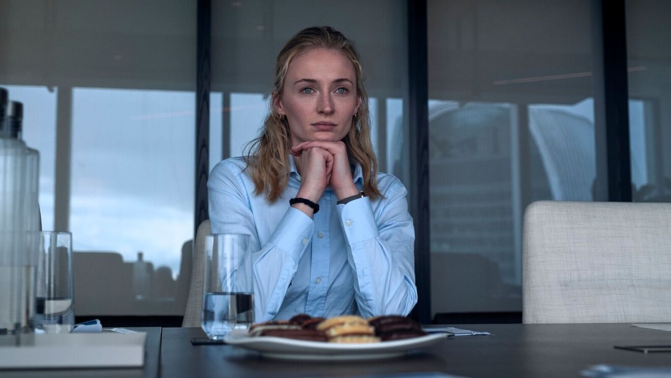 Zara (Sophie Turner) in a light blue shirt deep in thought at dining table