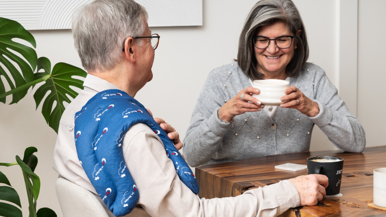 Two people drinking coffee and one is wearing a Magic Bag