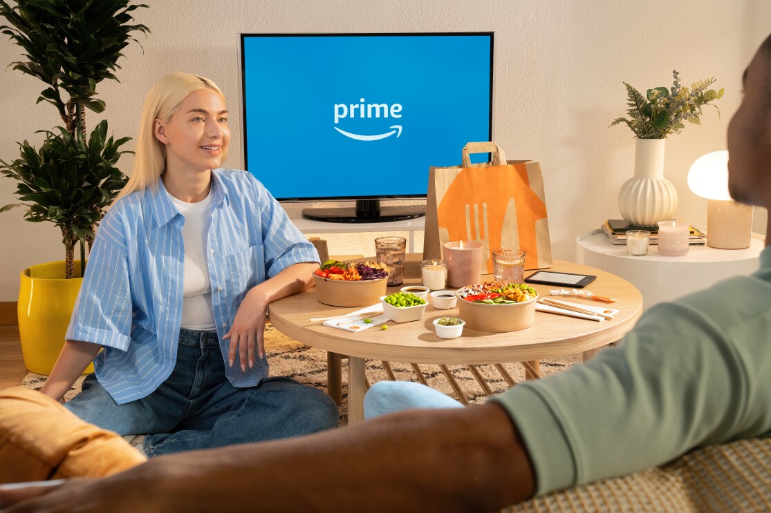 Eine Frau mit blonden Haaren sitzt am Tisch mit einer Lieferando-Lieferung.