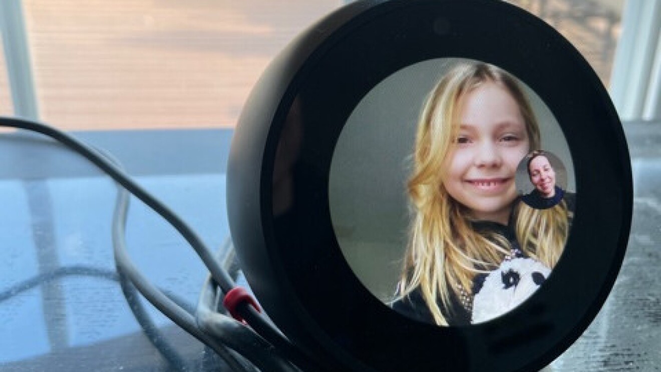 Katelyn is at her desk smiling while her mom, Andi, checks in on her via Echo Spot.