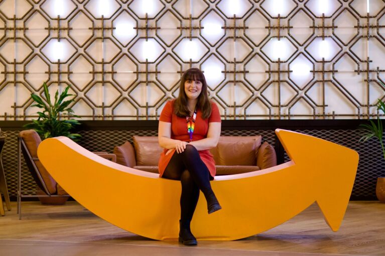 Cheerful employee relaxing on quirky yellow couch shaped as the Amazon smile in office lounge area
