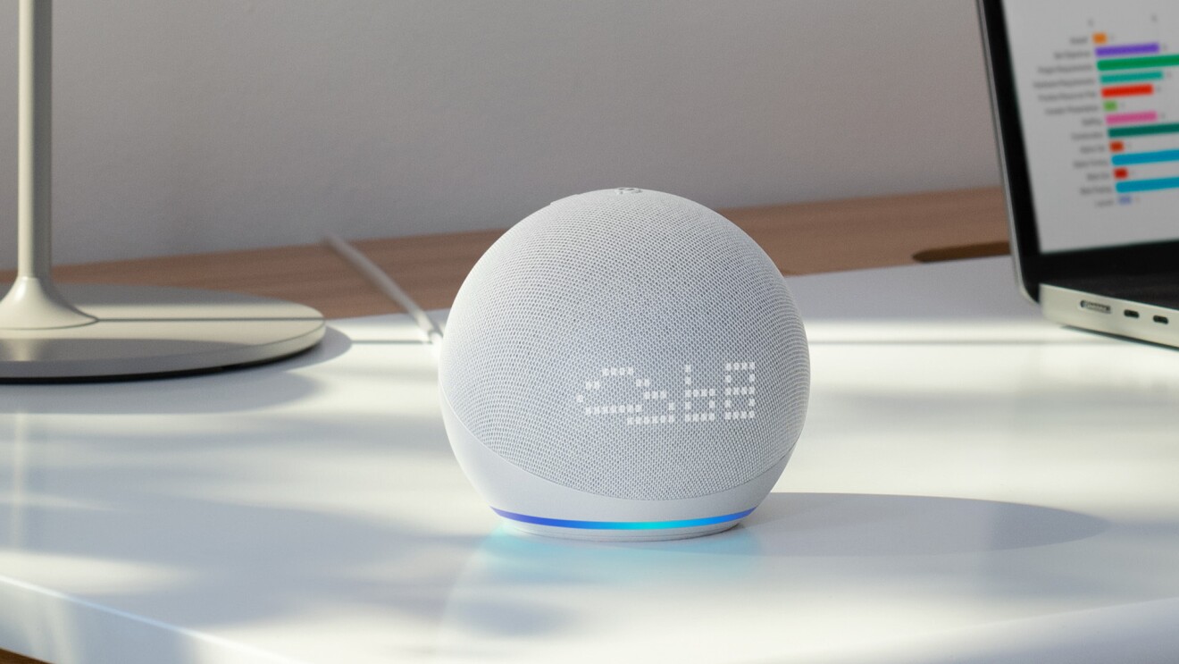 Dispositivo Alexa en una mesa de trabajo con el ordenador de fondo.