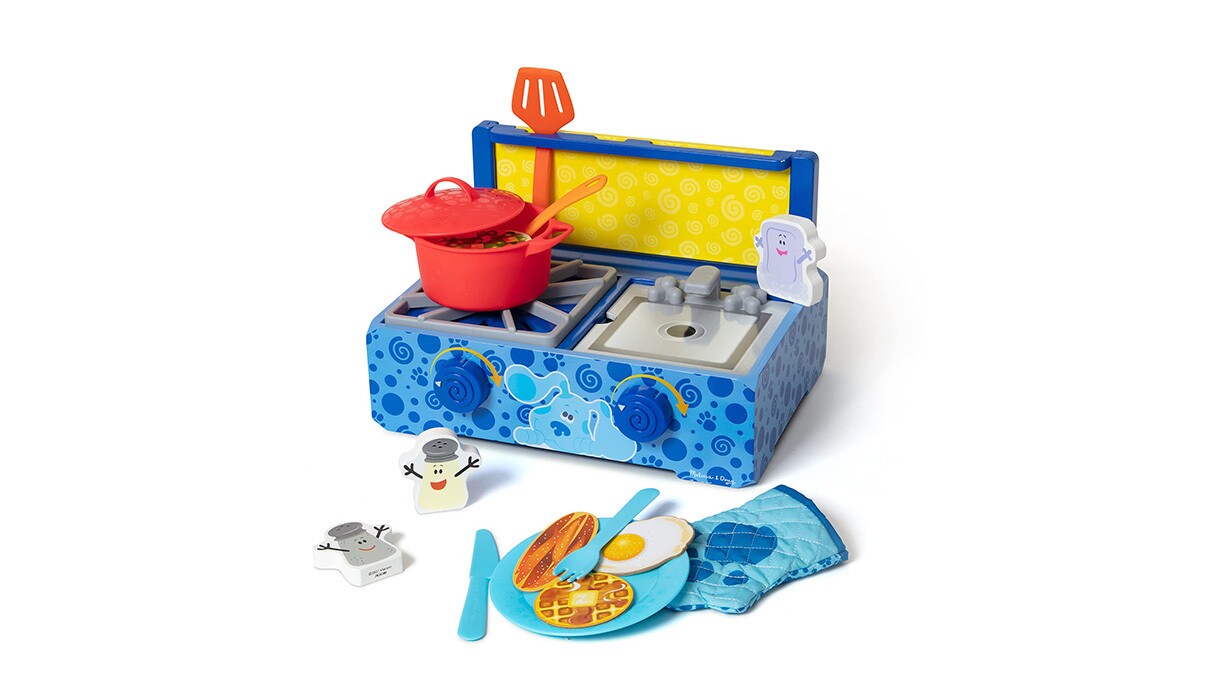 An image of a stove with a pot and spatula on it. There is also a plate, fork, and knife with bacon and eggs on it and an oven mitt in front of the stove.