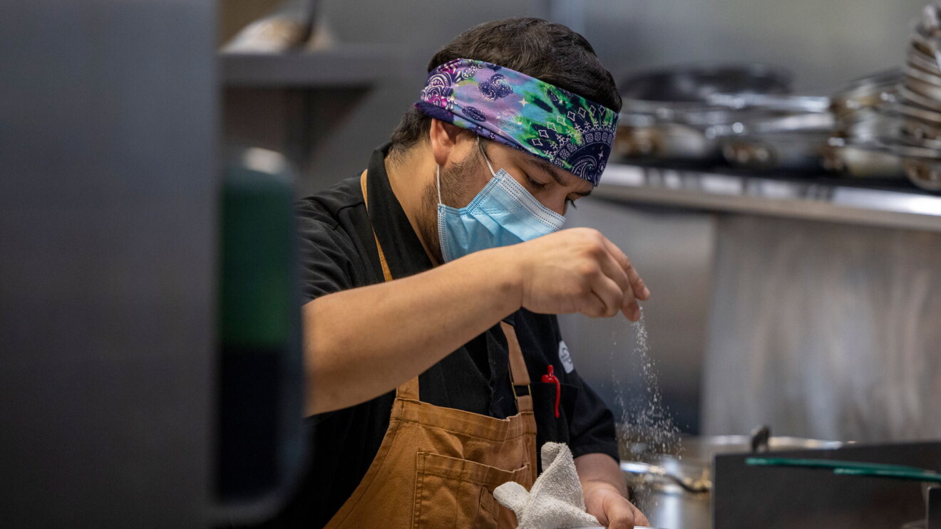 A cook at Eastvale Cafe prepares food in a kitchen.