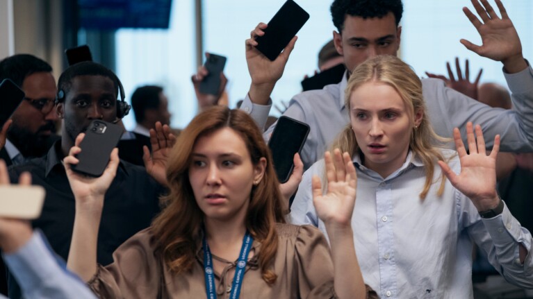 Group raises hands in surrender in a crowded office setting