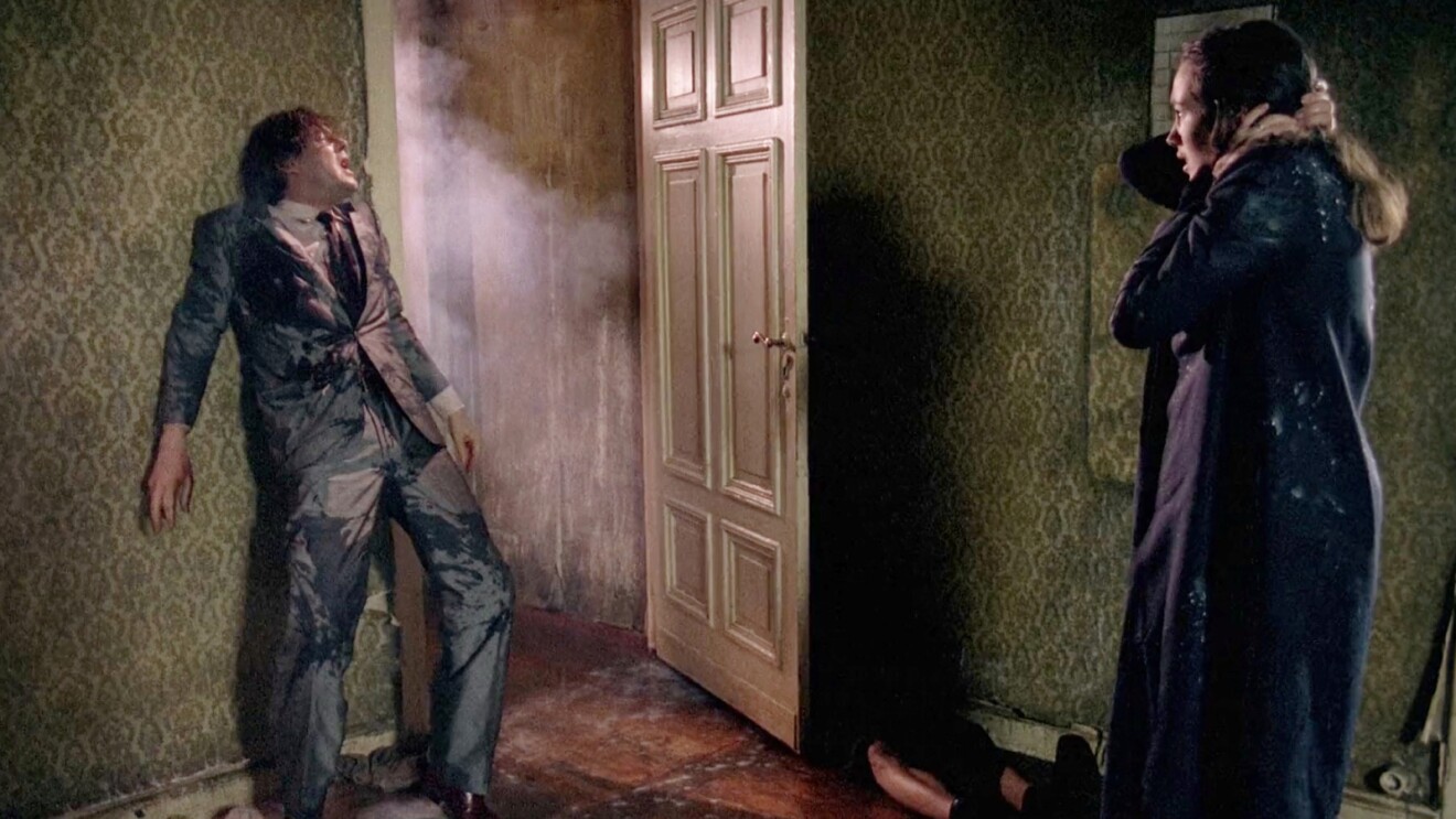 Man recoils from smoky doorway as woman watches in horror
