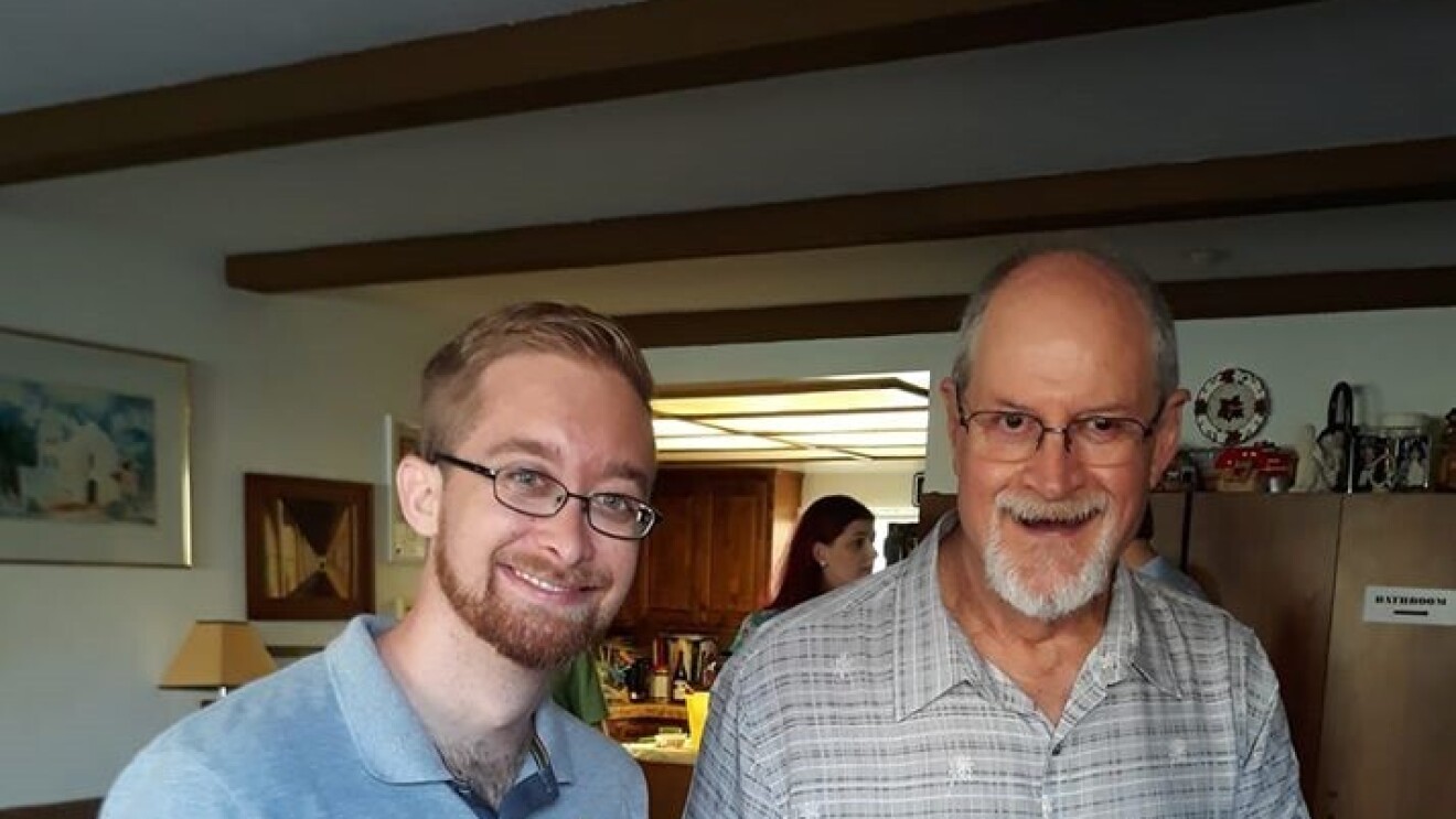 Two men stand together in a living room. Tim (left) received a kidney from his uncle Jerry (right) and pose together for an image.