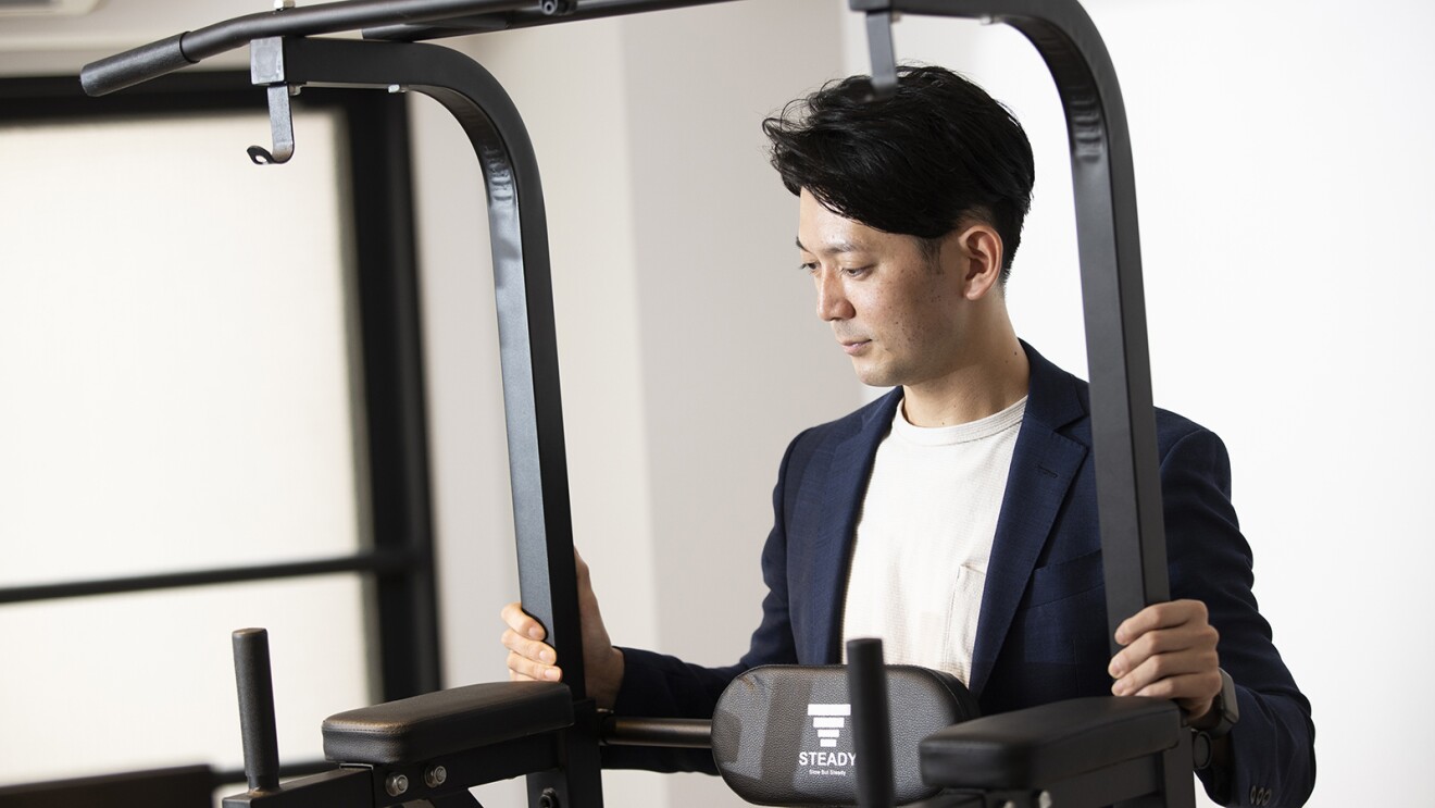 懸垂器具のつくりを確認するように見る山田さん