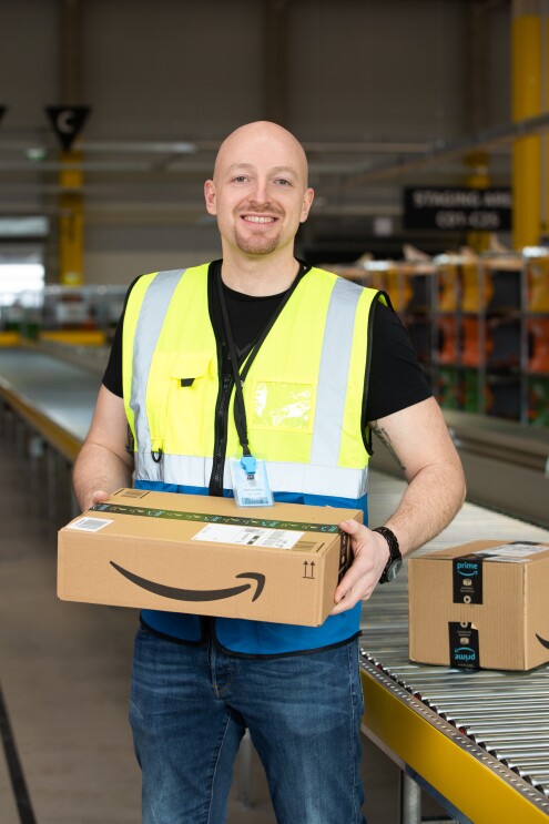 Ein Mann in Sicherheitsweste mit einem Päckchen in der Hand.