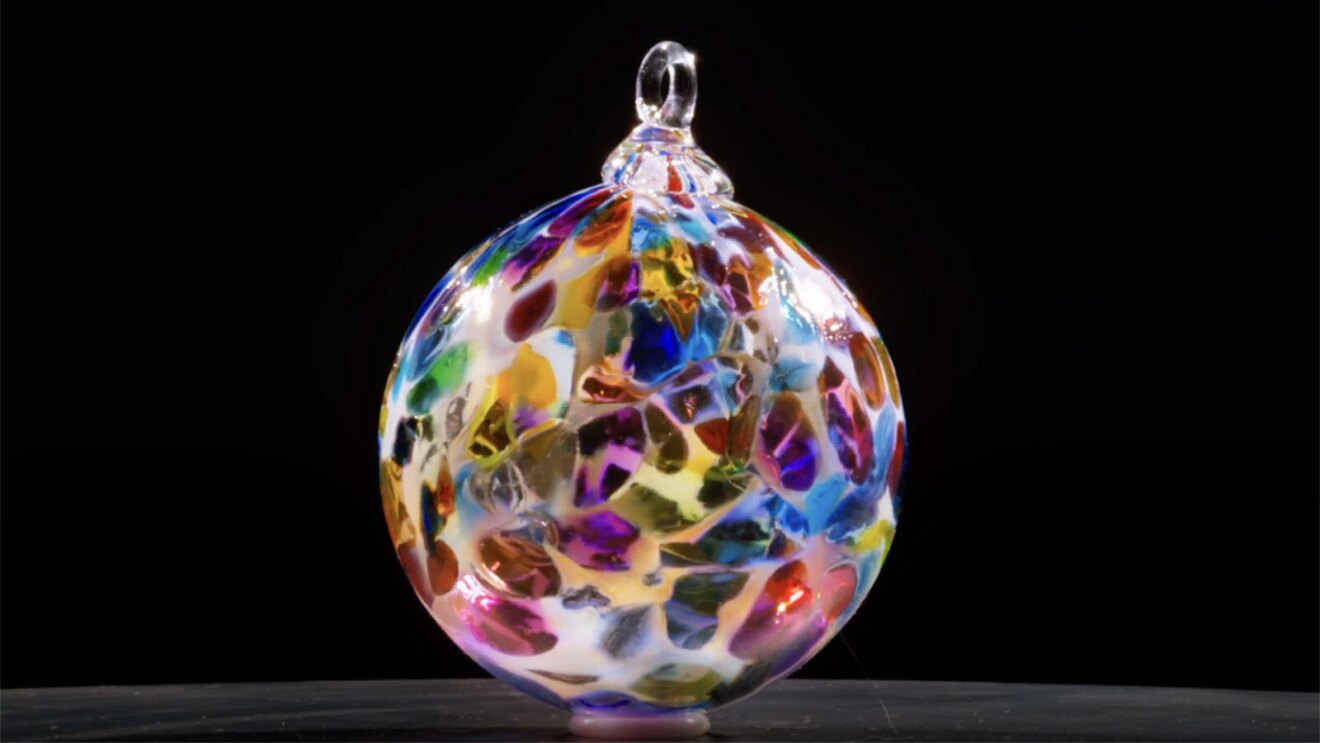 A multi-color piece of blown glass on a black background.