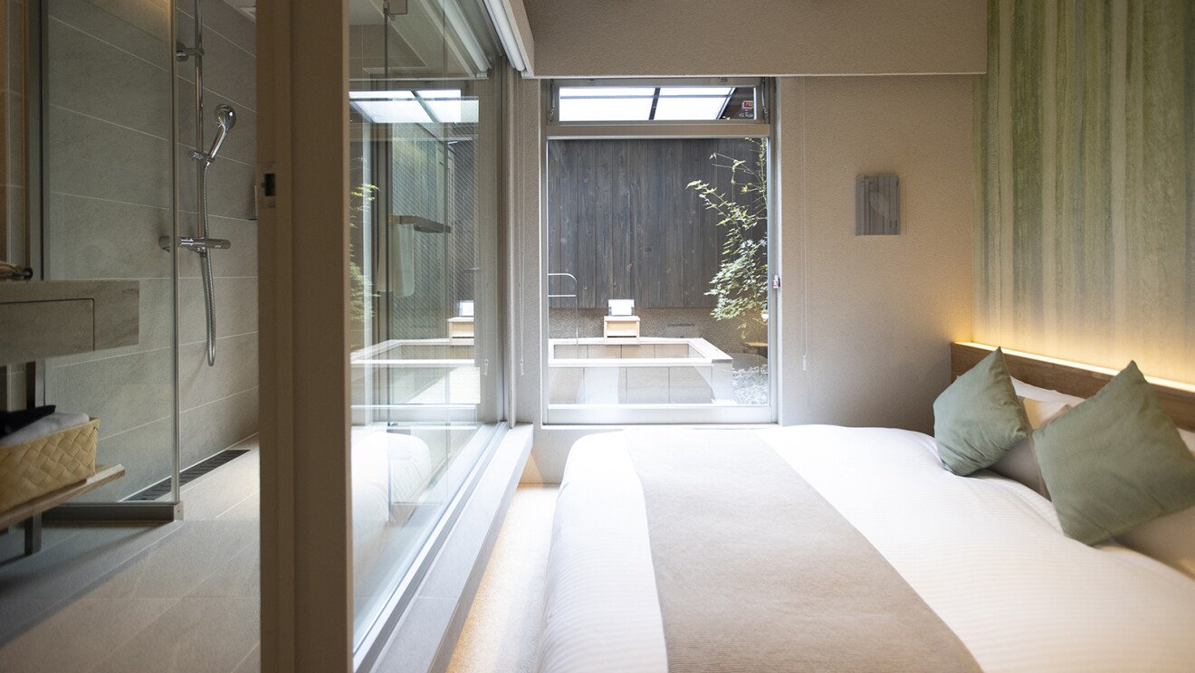 ベッドの向こうの窓の先に露天風呂が見える