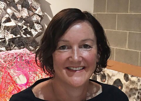 A candid photo of Jodi Stuart. There are pieces of artwork in the background.