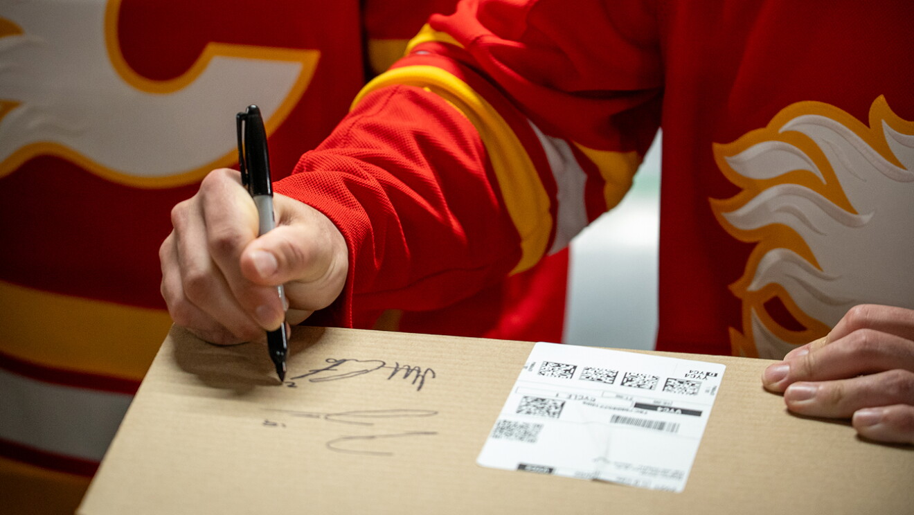 Two Calgary Flames hockey players packing and shipping Amazon boxes