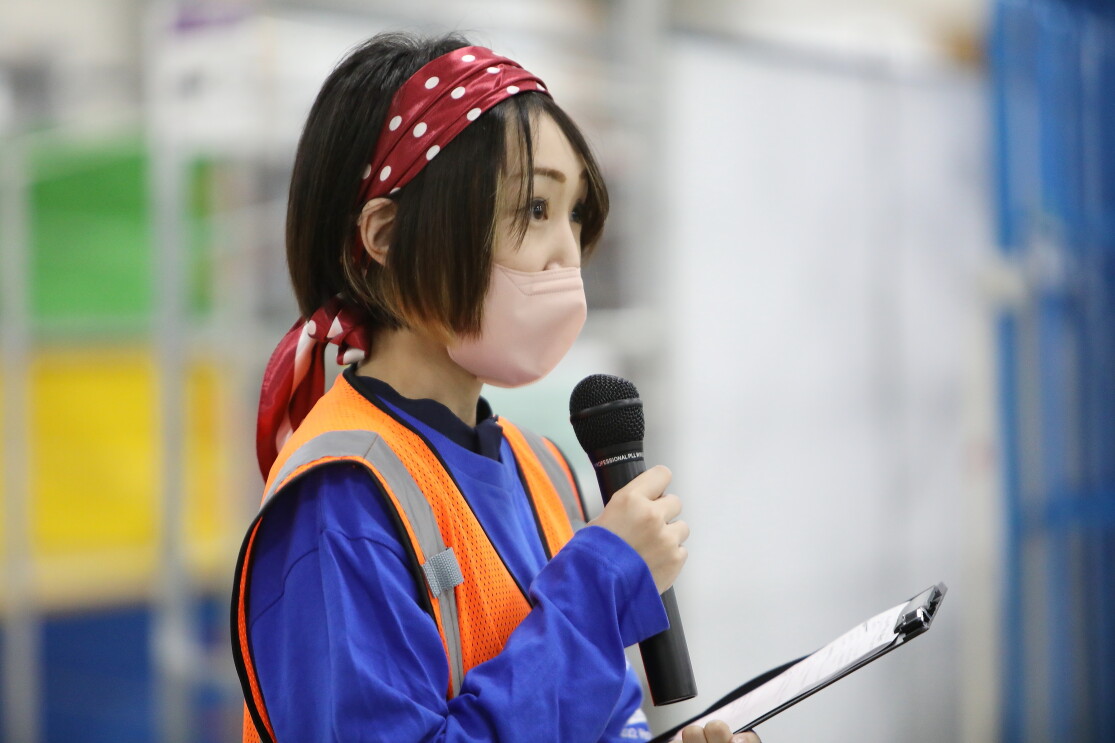 頭にバンダナを巻き、マイクを握って話をする女性。中野さん。口にはマスクをしている