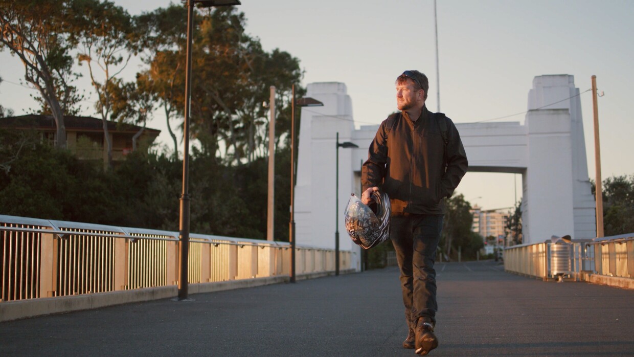 Man walks across a bridge at sunset.