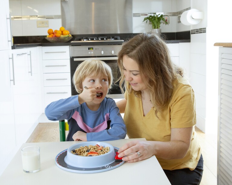 Sophia Proctor and her son sitting at the dinner table with a Munchy Play Bowl full of cereal.
